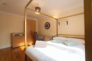 Ein Schlafzimmer mit Bett, Stuhl, Kleiderschrank, einer Uhr und einer Pendelleuchte.