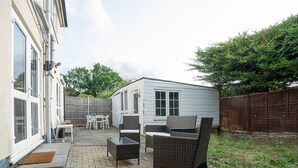 A patio area with outdoor furniture, a small shed, and a wooden fence. - Free Parking 7 Beds Contractor & Large Groups (Reading)