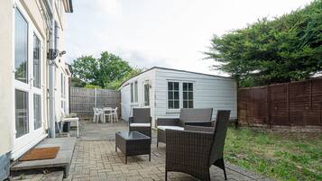 A patio area with outdoor furniture, a small shed, and a wooden fence.