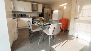 A compact kitchen with white cabinets, a glass dining table, and two chairs. - Free Parking 7 Beds Contractor & Large Groups (Reading)