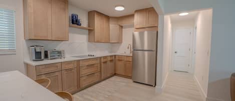 Une cuisine moderne avec des meubles en bois, un réfrigérateur en acier inoxydable et un plan de travail blanc.