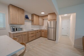 Eine moderne Küche mit Holdekor-Schränken, einem Edelstahl-Kühlschrank und einer weißen Arbeitsplatte.
