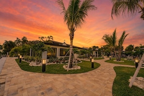 A resort with a paved walkway, palm trees, and a building with large windows. - 18 On the Bay Suite #1 (Indian Rocks Beach)