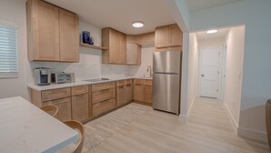 A modern kitchen with wooden cabinets, a stainless steel refrigerator, and a white countertop. - 18 On the Bay Suite #1 (Indian Rocks Beach)