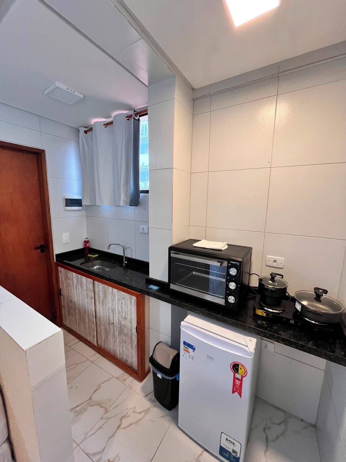 Una cocina compacta con horno integrado, un refrigerador pequeño y un basurero.