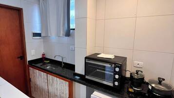Una cocina compacta con horno integrado, un refrigerador pequeño y un basurero.