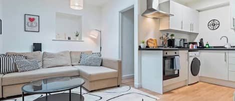 A modern apartment with a living area, kitchenette, and a dining table.