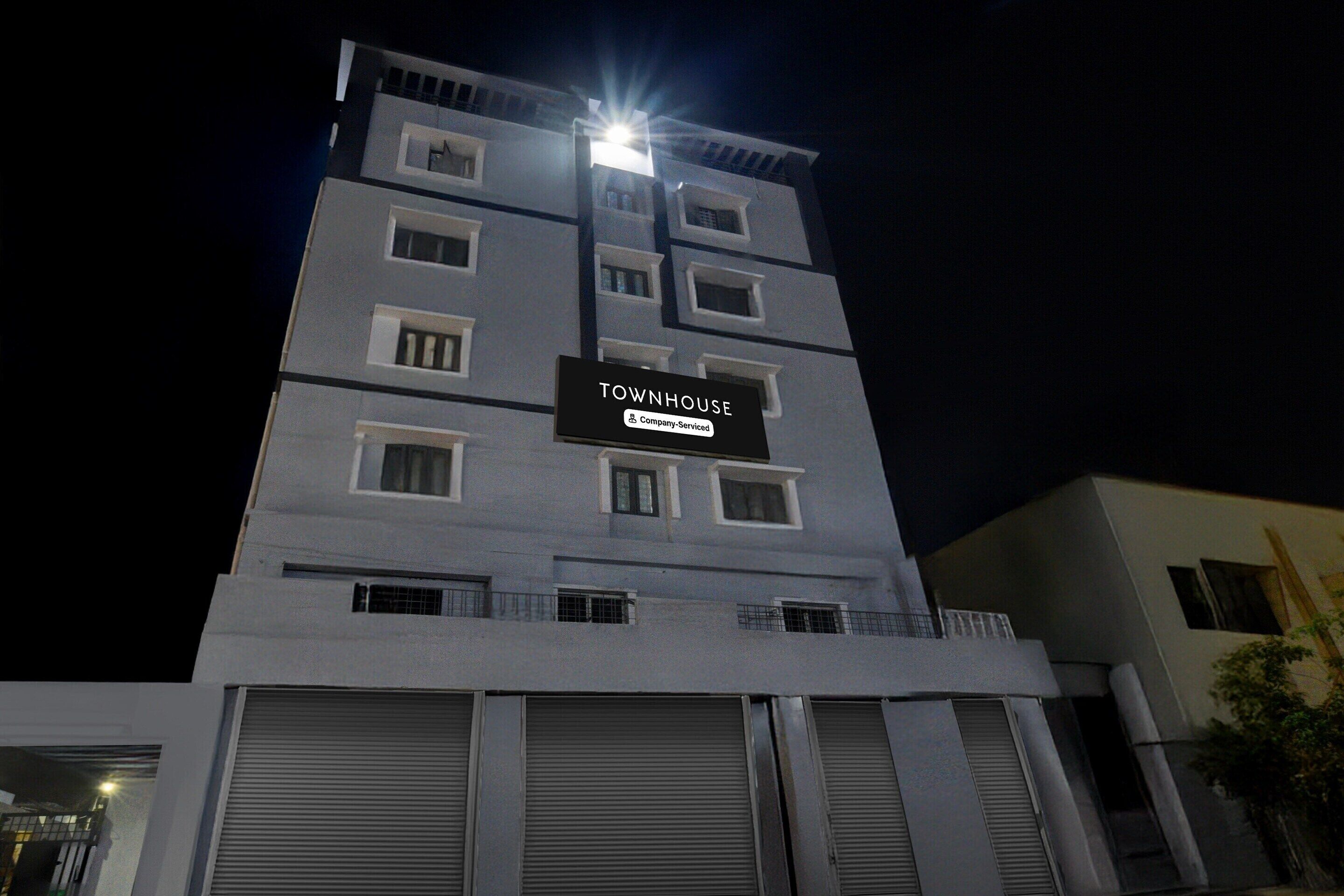 A multi-story building with a sign that reads 'TOWNHOUSE Company-Serviced.'