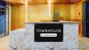 A reception desk with a sign reading 'TOWNHOUSE & Company Serviced'. - Premium Vanasthalipuram Near (Hyderabad)