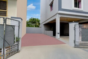 Uma entrada residencial com telhado vermelho e um caminho de acesso por portão.