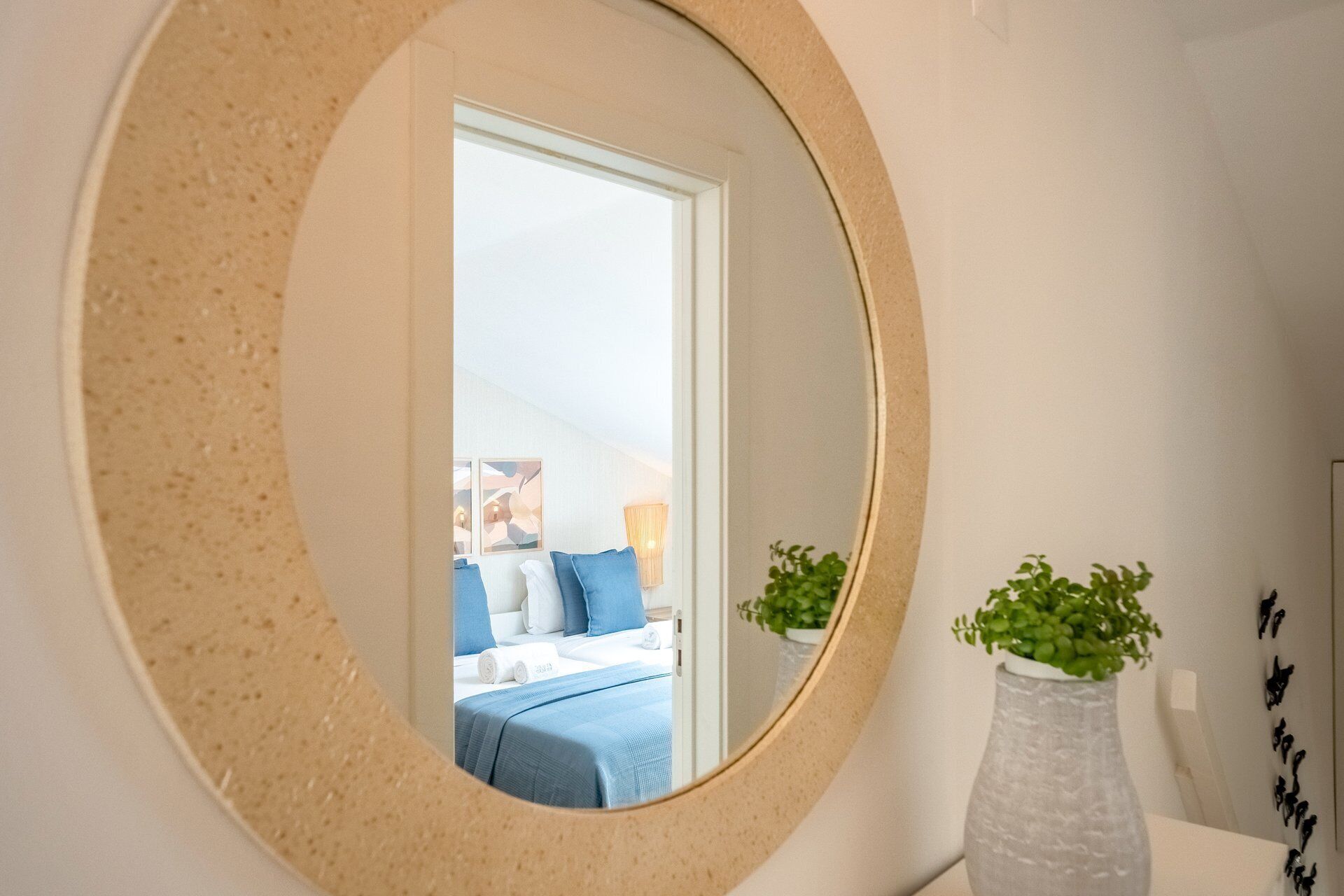 Quarto com uma cama, um espelho e um vaso com plantas.