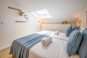 Ein Schlafzimmer mit Dachfenster, einem Bett mit aufgerollten Handtüchern und einem Nachttisch mit Lampe.