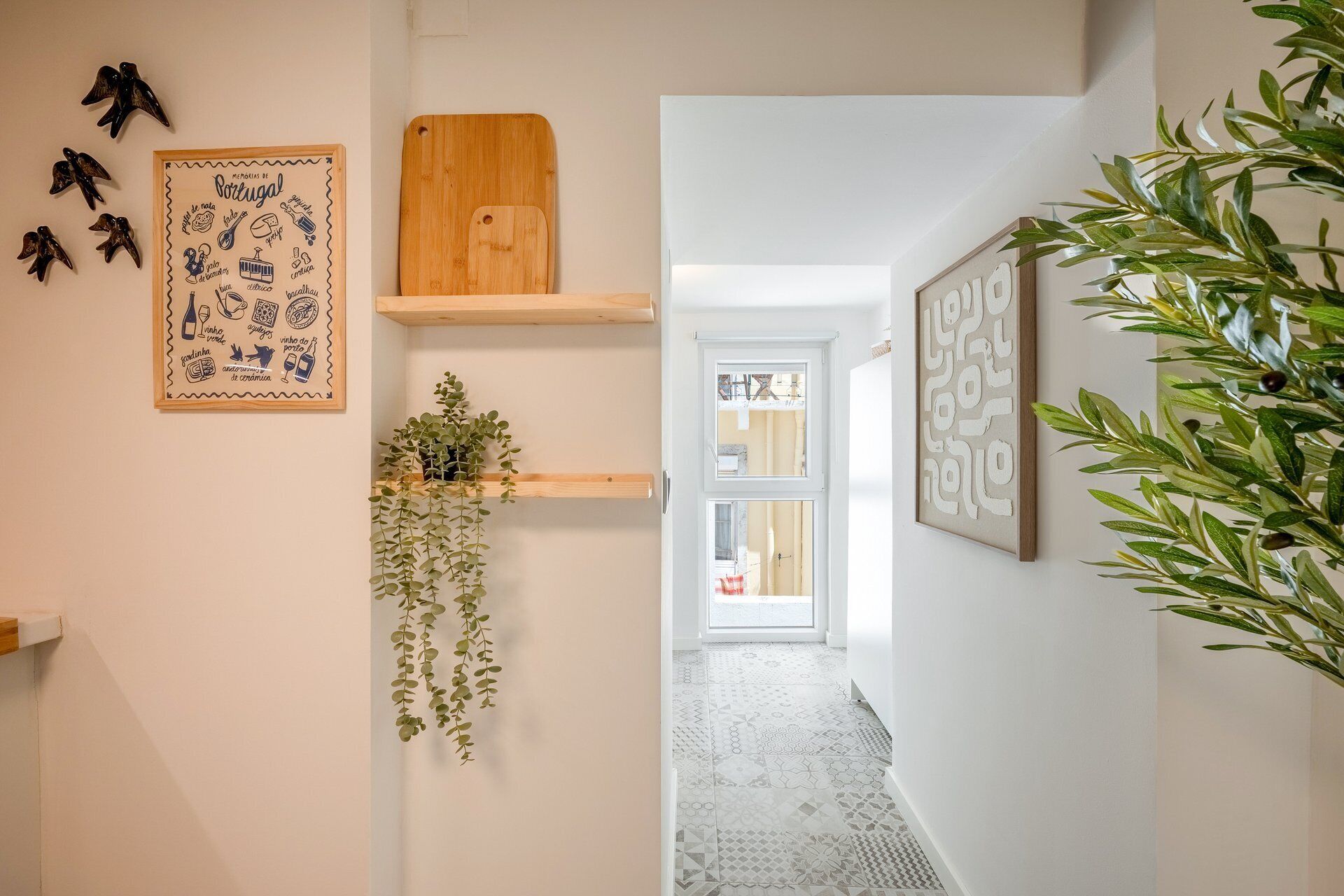 A hallway with a wooden shelf, a framed picture with text, a hanging plant, and a door leading to another room.