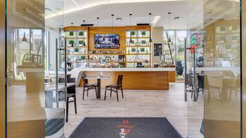 A bar area with a TV, shelves of bottles, and a counter. There are chairs and a table in the foreground.