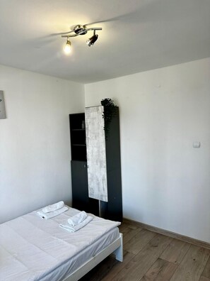 A bedroom with a bed, a wall-mounted shelf, and a hanging plant. - Chmielna 3-bedroom apartment in City Center,Pet Friendly (Warszawa)