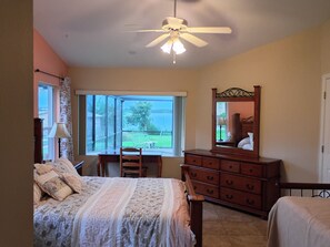 Une chambre à coucher comprenant un lit, une commode, un bureau et une fenêtre donnant sur l’extérieur.