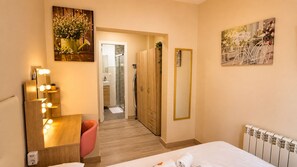 A hotel room with a bed, a vanity with lights, a mirror, and a door leading to a bathroom. - New Apartment next to the Cathedral (Granada)