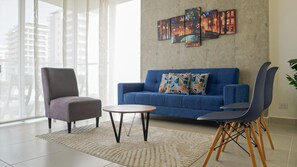 A living room with a blue sofa, a grey armchair, and a round coffee table. - a 10 minutos del centro historico y a 5 minutos de la playa apto amplio 2B / 2B (Cartagena de Indias)