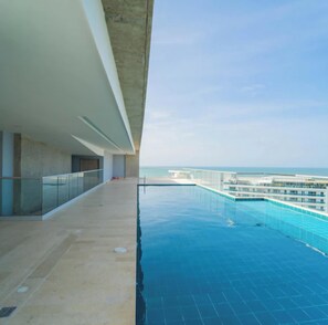Ein moderner Poolbereich mit freiem Blick auf das Meer, einer Glasumlaufung und einer Betonkonstruktion.