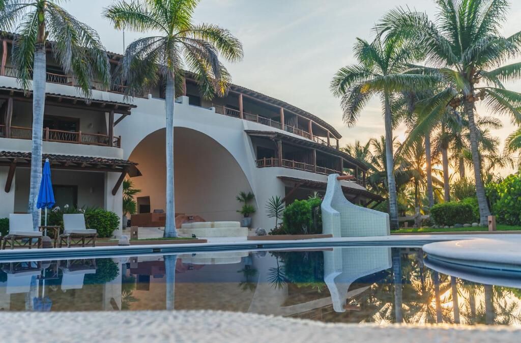 A resort with a pool, palm trees, and a building with balconies.