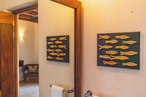 Un baño con toallero, espejo y dos cuadros con motivos de peces en la pared.