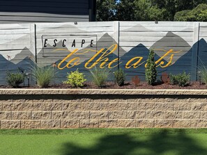 A wall with a decorative sign that reads 'ESCAPE to the arts.' - Escape to the Arts, Golf Sim, Theater, Hot Tub (Charlotte)