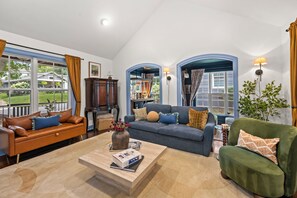 A spacious living room with a large window, a fireplace, and a cozy seating area. - Escape to the Arts, Golf Sim, Theater, Hot Tub (Charlotte)