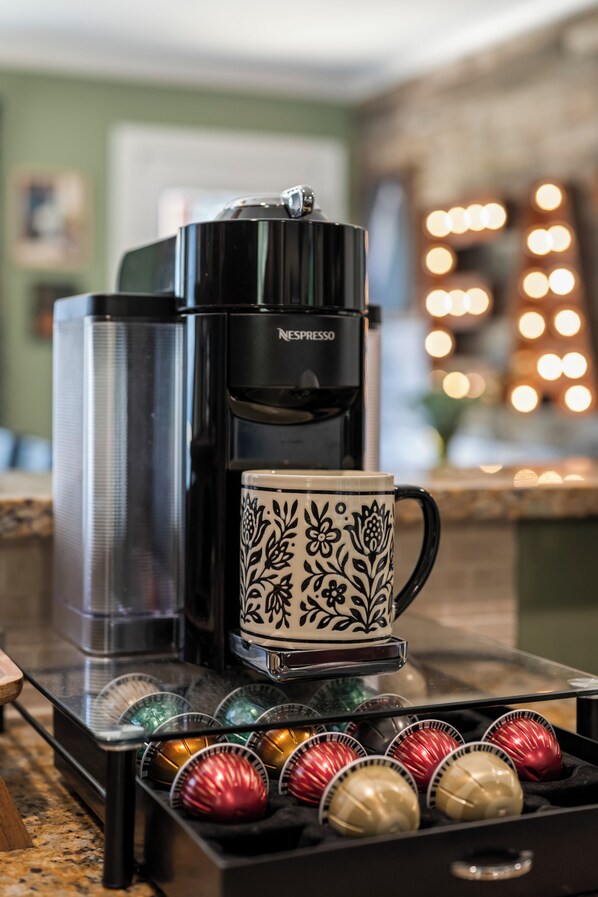 Une machine à café, une tasse et une boîte de capsules de café sont posés sur un plan de travail.
