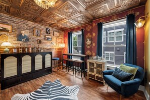 A bar area with a wooden ceiling, a zebra-patterned rug, a blue armchair, and a window with curtains. - Escape to the Arts, Golf Sim, Theater, Hot Tub (Charlotte)