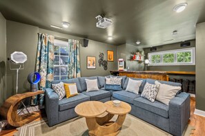 A modern living room with a sectional sofa, a wooden coffee table, and a bar area with a popcorn machine. - Escape to the Arts, Golf Sim, Theater, Hot Tub (Charlotte)