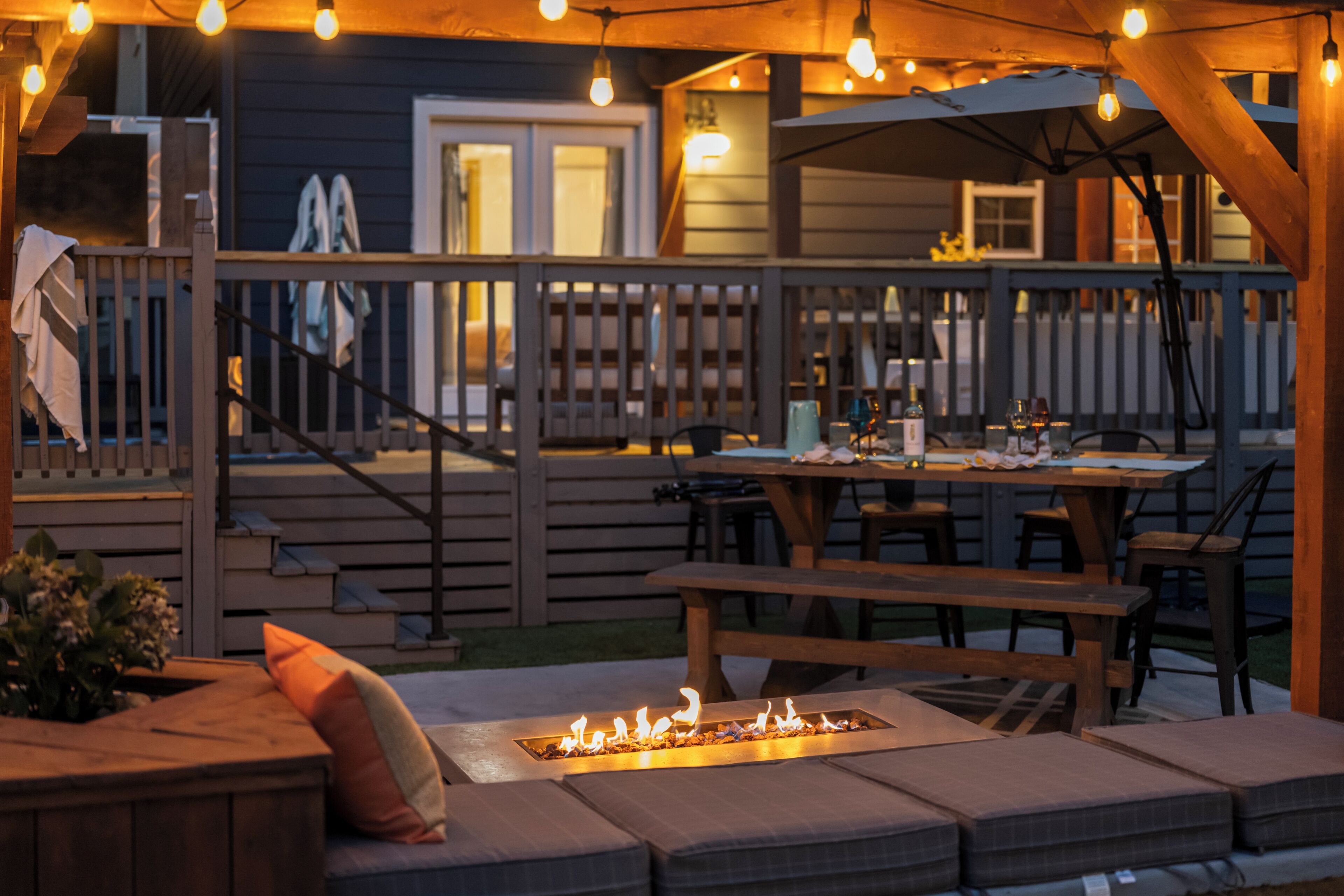 An outdoor patio with a fire pit, wooden deck, and seating area.