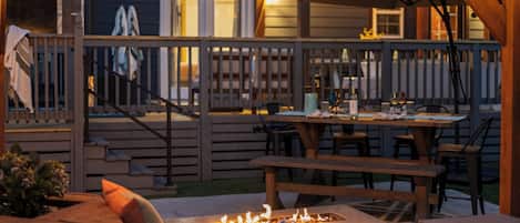 An outdoor patio with a fire pit, wooden deck, and seating area.