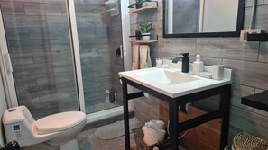 A bathroom with a toilet, a sink, and a shower area.