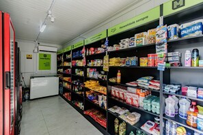 A grocery store aisle with shelves stocked with various products including snacks, beverages, and household items. - Apto com Piscina e Garagem no Roçado (São José)