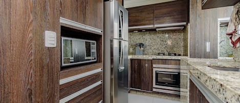 A modern kitchen with wooden cabinetry, stainless steel appliances, and granite countertops.