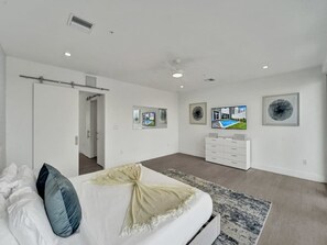 Une chambre à coucher avec un lit, une télévision, une commode et des tableaux encadrés accrochés au mur.