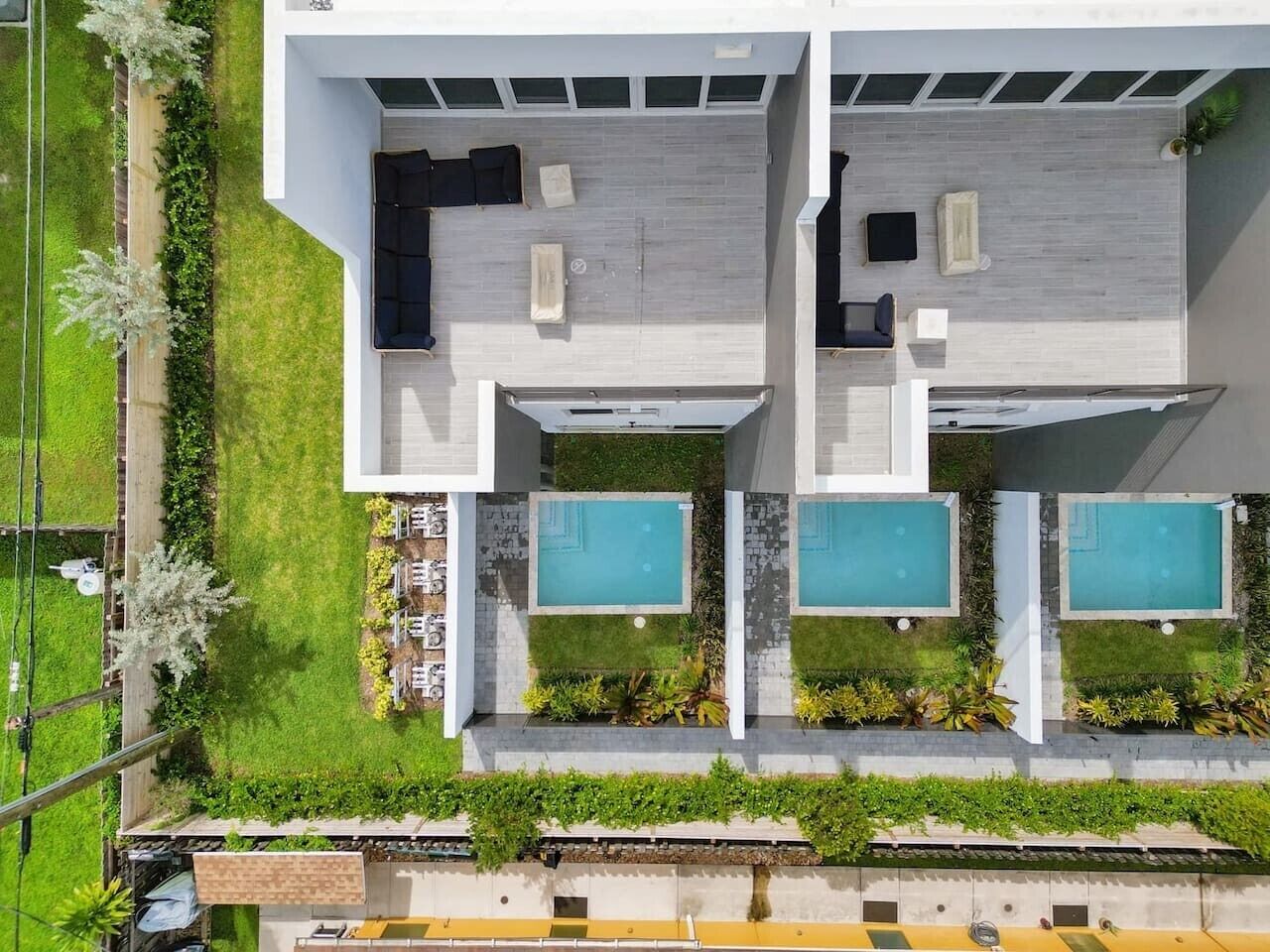 Un edificio moderno con dos piscinas, una terraza en la azotea y un césped cuidado.