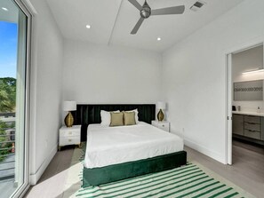 A modern bedroom with a large bed, a ceiling fan, and a view of the outdoors. - New Ft Lauderdale Luxe Home + Pool near Las Olas (Fort Lauderdale)