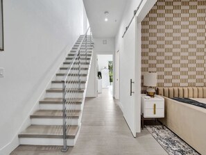 A modern interior with a staircase, a sofa, and a patterned wall. - New Ft Lauderdale Luxe Home + Pool near Las Olas (Fort Lauderdale)