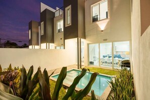 A modern two-story house with a swimming pool, large windows, and a well-lit exterior. - New Ft Lauderdale Luxe Home + Pool near Las Olas (Fort Lauderdale)