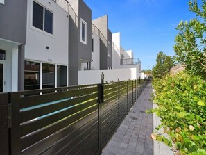 A modern building with a gated entrance, a paved pathway, and a well-maintained hedge. - New Ft Lauderdale Luxe Home + Pool near Las Olas (Fort Lauderdale)
