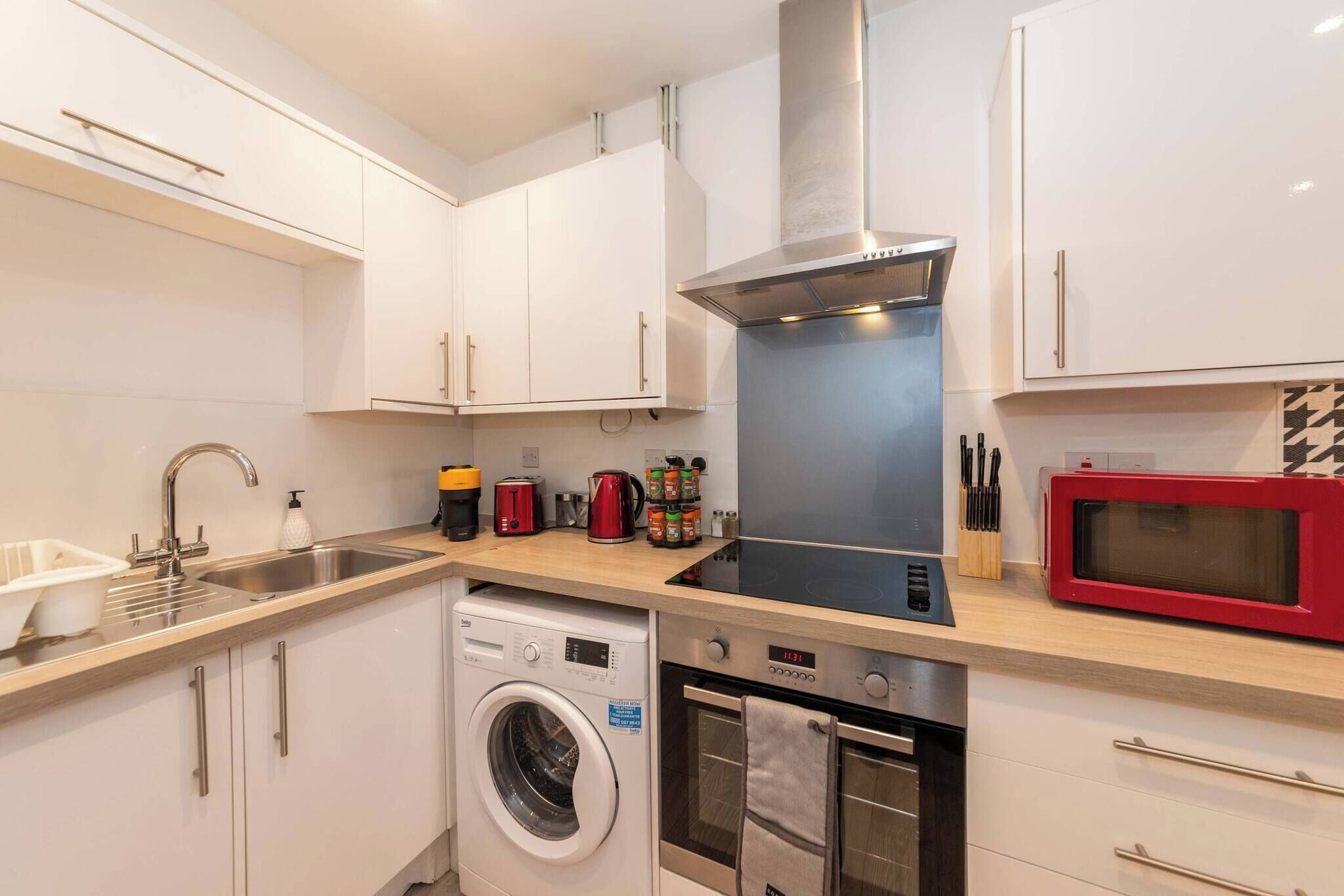 A compact kitchen with a washing machine, a microwave, and a stove.
