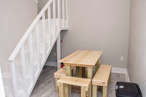 A staircase with white railings, a wooden table with benches, and a black suitcase on the floor.