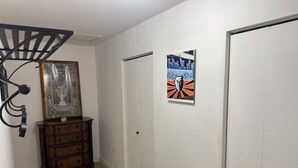 A hallway with a wooden dresser, a framed picture, and a poster on the wall.