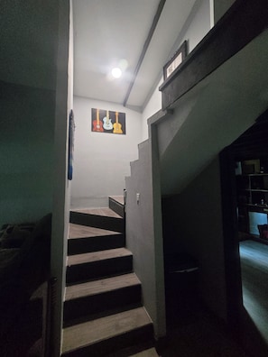 A staircase with a handrail, a wall-mounted picture, and a ceiling light.