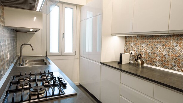 A modern kitchen with a gas stove, stainless steel sink, and white cabinets. - Unique property: 120 square meters - 150 meters from the beach - garage (Lido di Jesolo)