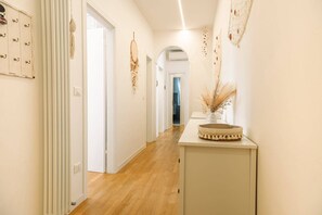 A hallway with a wooden floor, white walls, and a white cabinet with a decorative item on top. - Unique property: 120 square meters - 150 meters from the beach - garage (Lido di Jesolo)
