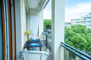 A balcony with a table set for two, a wicker chair, and a view of the cityscape. - Unique property: 120 square meters - 150 meters from the beach - garage (Lido di Jesolo)