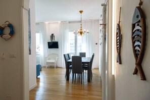 A dining area with a chandelier, a television on the wall, and a view of the outside. - Unique property: 120 square meters - 150 meters from the beach - garage (Lido di Jesolo)