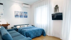 A modern bedroom with a bed, a sofa, and a TV. - Unique property: 120 square meters - 150 meters from the beach - garage (Lido di Jesolo)